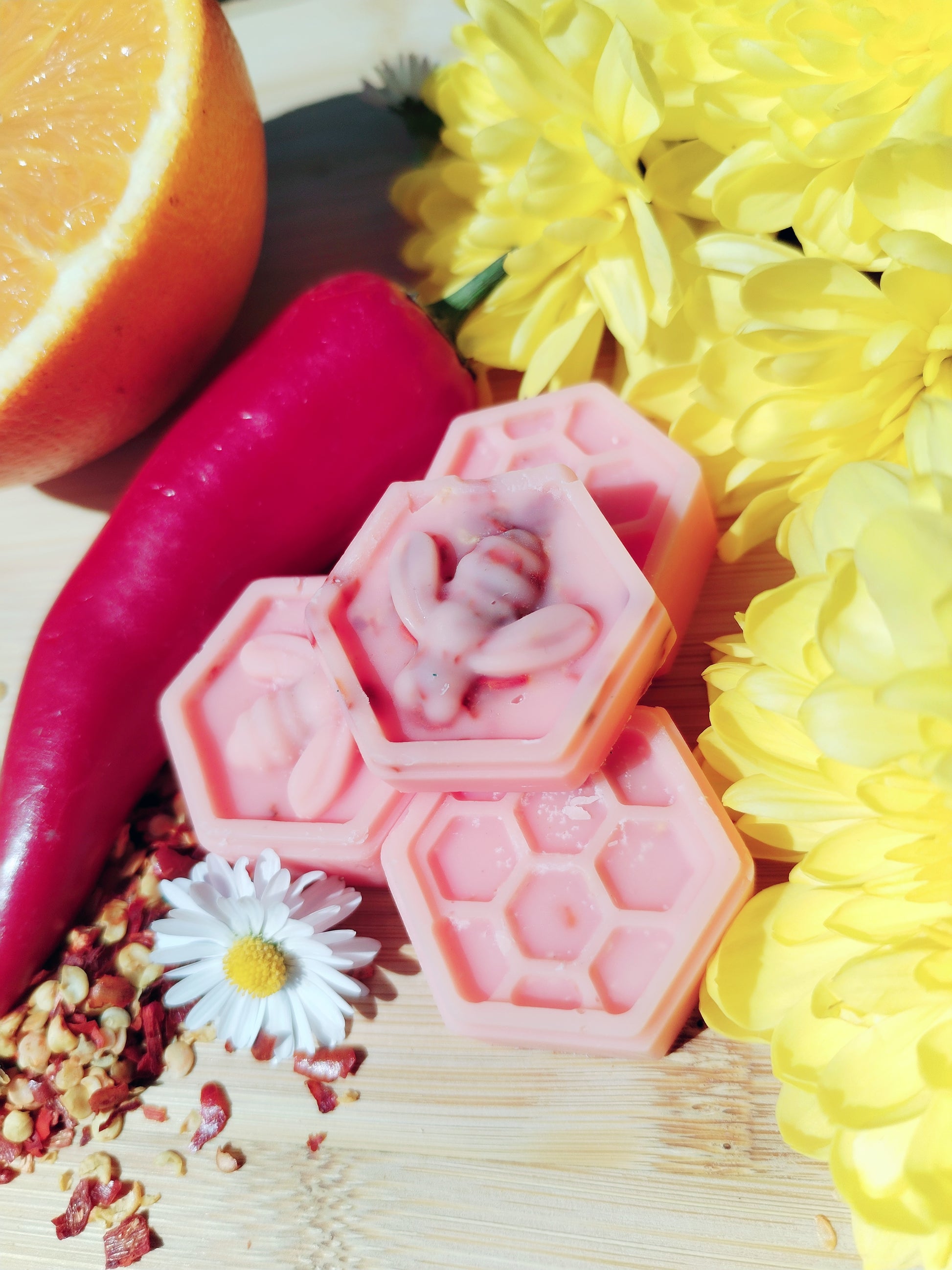 Handcrafted Honeycomb Wax Melts with Bee, Chilli Pepper, Orange, Daisy, and Yellow Flowers on Bamboo Chopping Board - A Symbol of Natural Delight and Mystical Ambiance