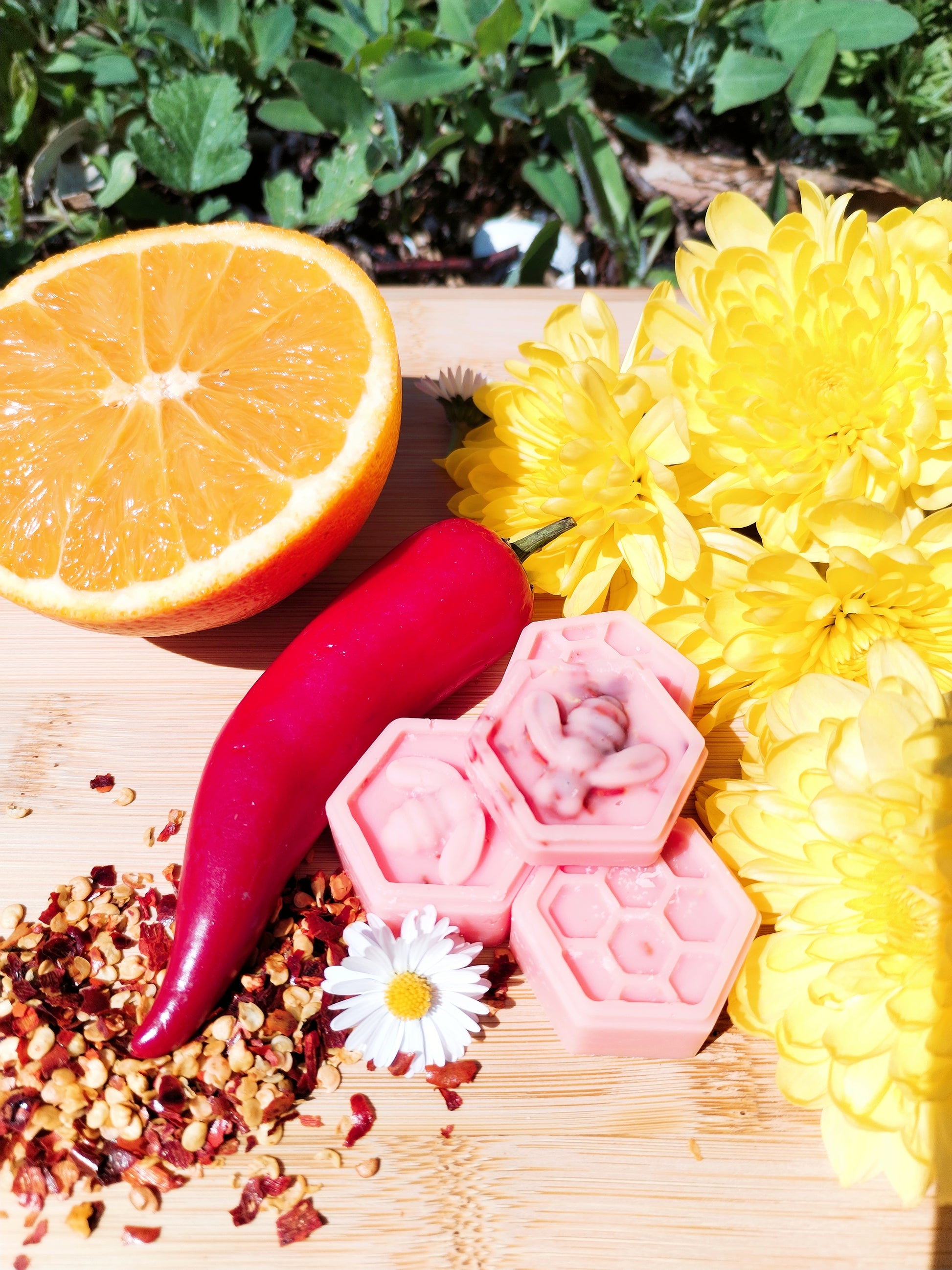 Handcrafted Honeycomb Wax Melts with Bee, Chilli Pepper, Orange, Daisy, and Yellow Flowers on Bamboo Chopping Board - A Symbol of Natural Delight and Mystical Ambiance