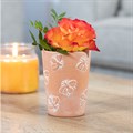 Terracotta Bee Pattern Plant Pot with Orange Flower and Candle: A charming terracotta pot with an orange flower bloom inside, accompanied by a lit yellow candle in the background. The scene is set on a coffee table with a glimpse of a sofa in the background.
